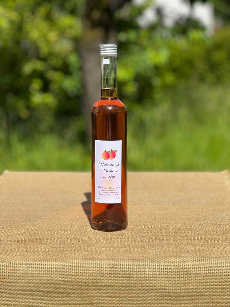 Eine Flasche Pfirsichlik&ouml;r auf einem Tisch mit idyllischem gr&uuml;nen Hintergrund.
