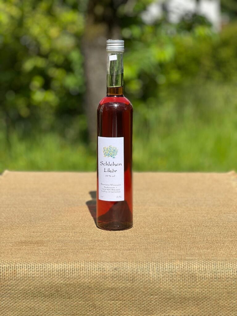 Eine Flasche Schlehen-Lik&ouml;r auf einem Tisch mit idyllischem gr&uuml;nen Hintergrund.