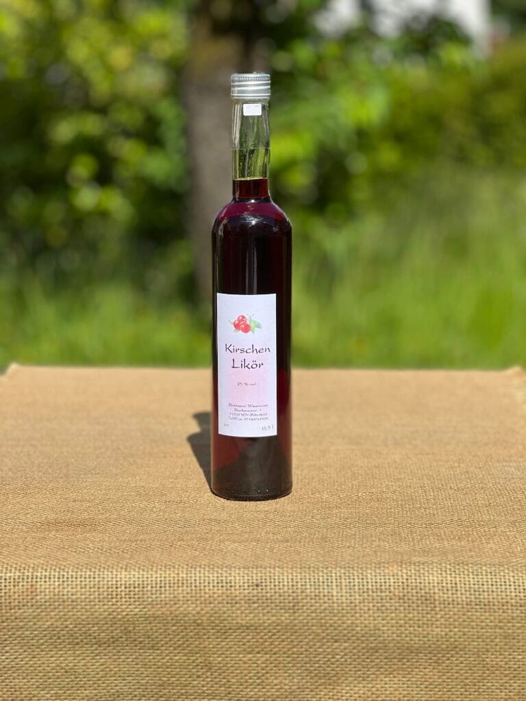 Eine Flasche Kirschen-Lik&ouml;r auf einem Tisch mit idyllischem gr&uuml;nen Hintergrund.