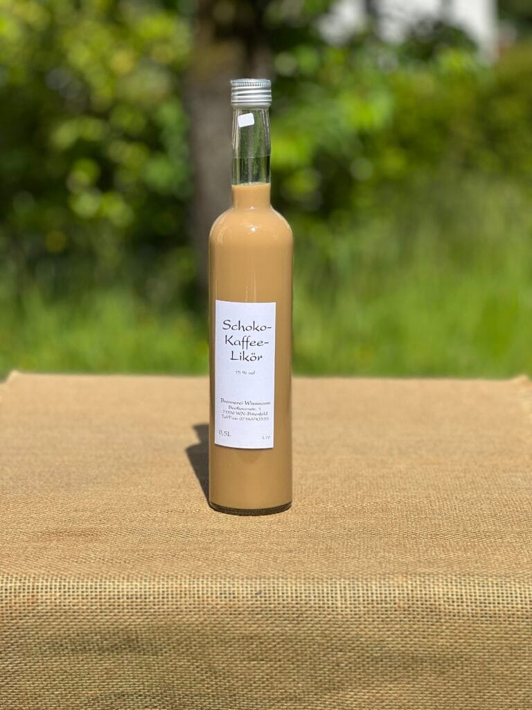 Eine Flasche Schoko-Kaffee-Lik&ouml;r auf einem Tisch mit idyllischem gr&uuml;nen Hintergrund.