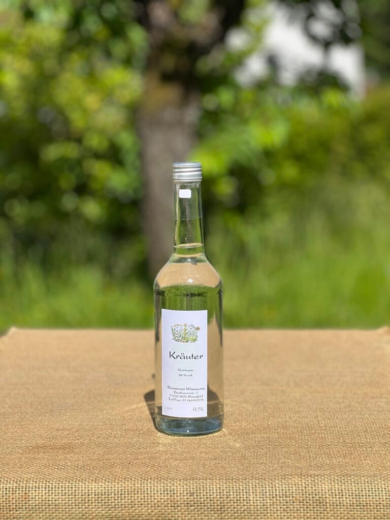 Eine Flasche Kr&auml;uterbrand auf einem Tisch mit idyllischem gr&uuml;nen Hintergrund.