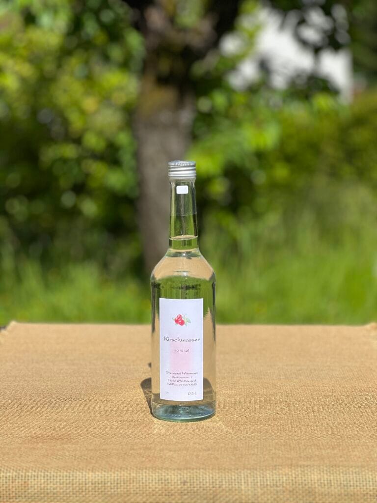 Eine Flasche Kirschwasser auf einem Tisch mit idyllischem gr&uuml;nen Hintergrund.