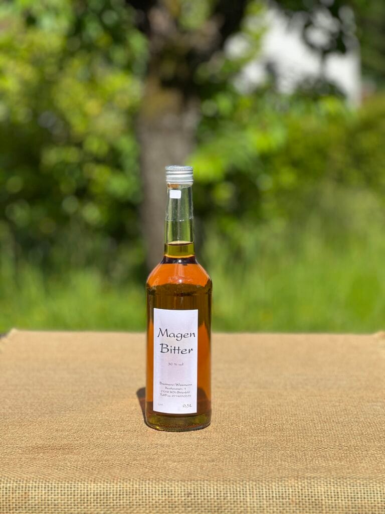Eine Flasche Magenbitter auf einem Tisch mit idyllischem gr&uuml;nen Hintergrund.