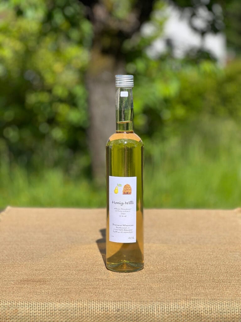 Eine Flasche Honig-Williams auf einem Tisch mit idyllischem gr&uuml;nen Hintergrund.