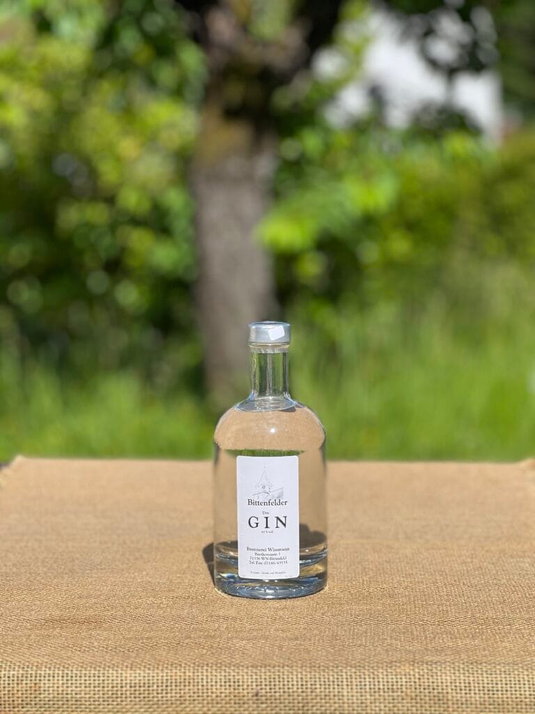 Eine Flasche Bittenfelder Gin auf einem Tisch mit idyllischem gr&uuml;nen Hintergrund.