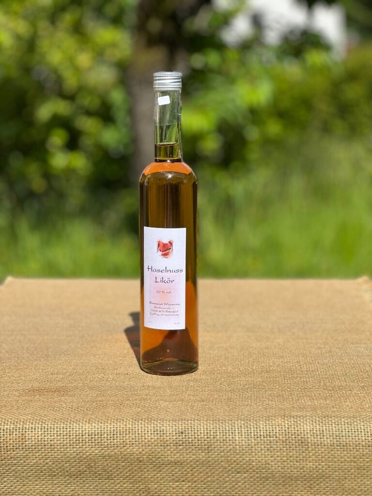 Eine Flasche Haselnuss-Lik&ouml;r auf einem Tisch mit idyllischem gr&uuml;nen Hintergrund.